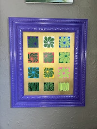 a purple and green framed painting on a wall